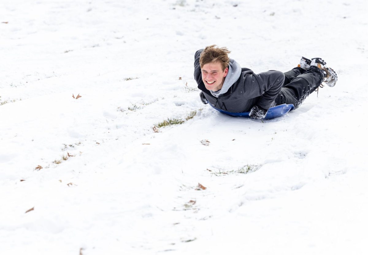 Freshman Ian Stanley sleds down a hill outside of Van Meter Hall on Wednesday, Feb. 19, 2025. Classes were canceled Wednesday due to a winter storm. 
