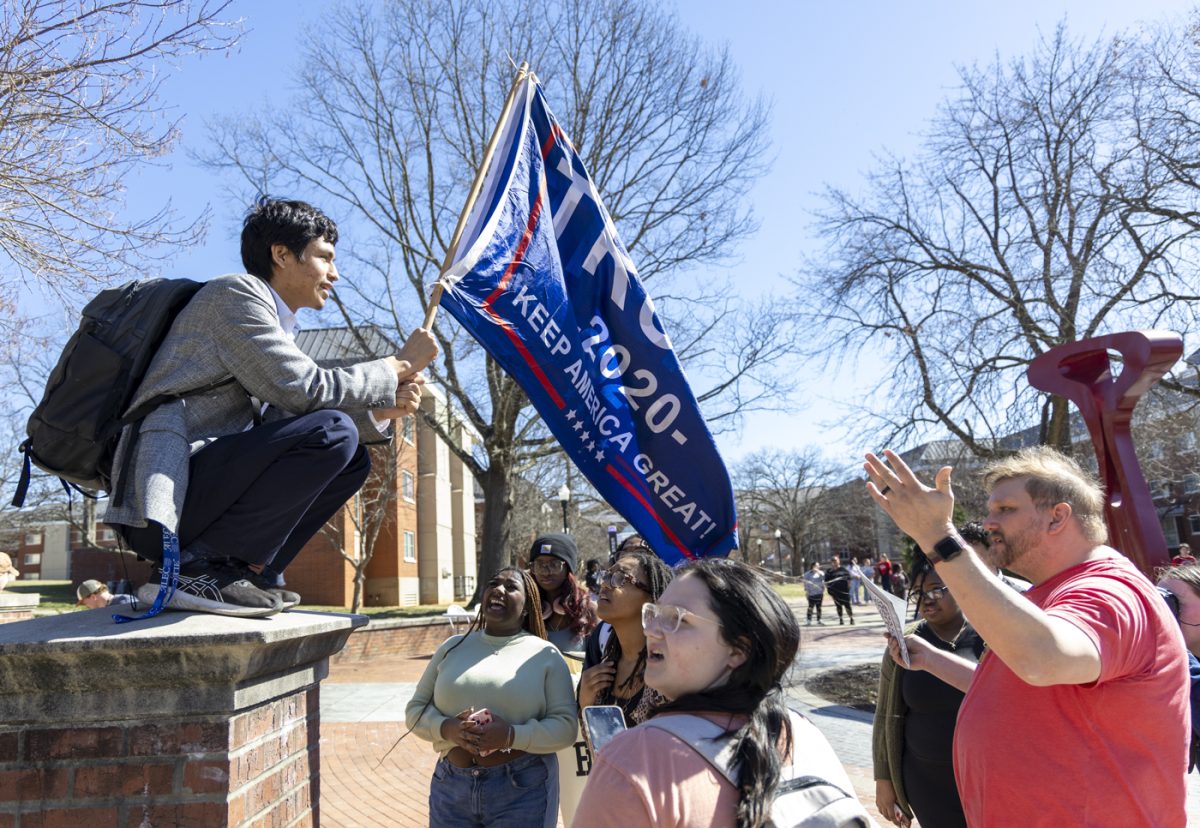 Gabriel Chambers holds a Trump 2020 campaign flag as protesters yell at him during a protest against anti Diversity, Equity and Inclusion legislation and actions at Centennial Mall on Western Kentucky Universities’ campus on Friday, February. 28, 2025.