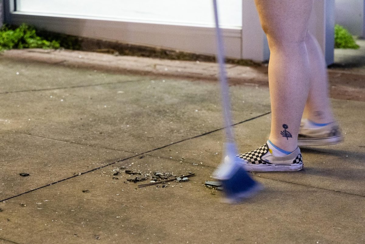 Pearce Ford Tower (PFT) Residence Assistant sweeps up glass after a window in the building was shattered from the inside on March. 13th, 2025.