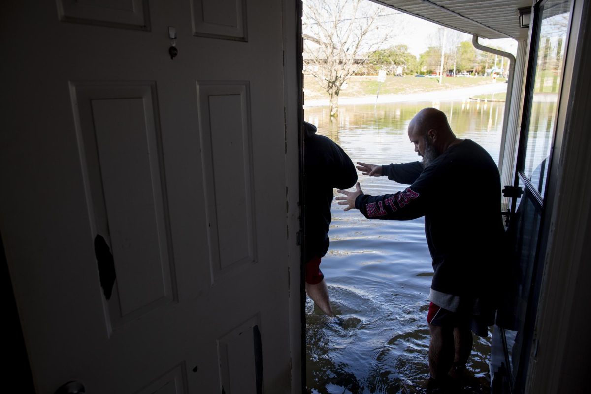 Dale Oliver helps his son Zachary Oliver walk down their doorstep covered by severe flooding left by historic storms in Bowling Green, Ky. on Monday, April 7, 2025. Zachary, who has autism, had to have an 8-hour operation for a heart condition earlier this month that has left him unable to exert much energy. During the storms, Dale was unsure if they would be able to get Zachary’s critical medication due to flood waters blocking roads. 